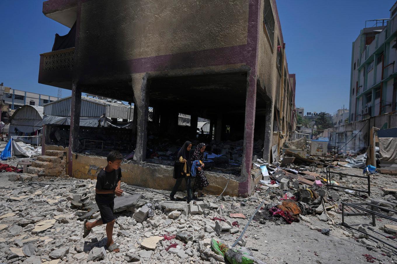 Palestinier undersöker förödelsen vid en skola som använts som skydd i Gaza och som bombades av Israel på torsdagen. Foto: Jehad Alshrafi/AP/TT