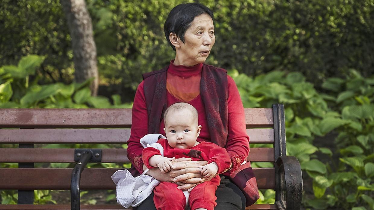 En kvinna med ett barn i en park i Peking. Kinas befolkning blir allt äldre, och barnafödandet minskar. Foto: Kevin Frayer/Getty Images