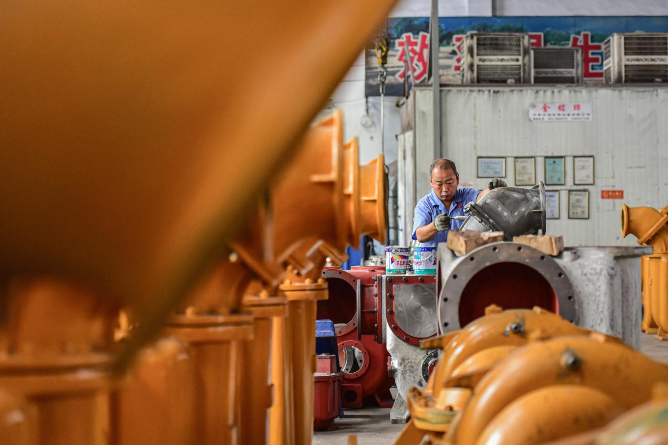 En arbetare i en fabrik som bygger vattenpumpar. Både offentliga verksamheter och statliga företag har svårt att betala ut löner i Kina. STR/AFP via Getty Images