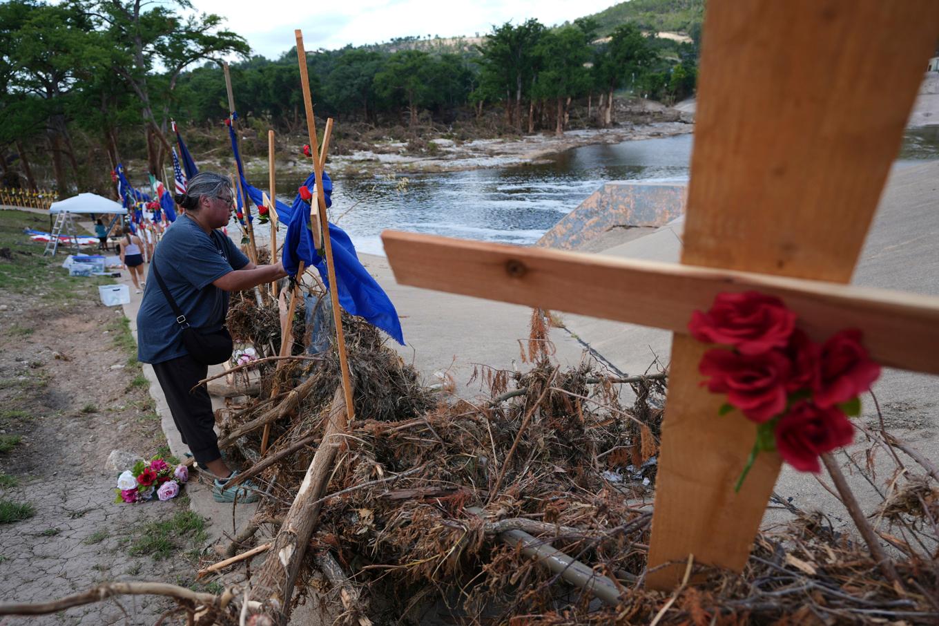 Människor kommer med blommor till det provisoriska minnesmärket efter översvämningens offer vid Guadalupefloden i Kerrville, Texas. Foto: Eric Gay/AP/TT