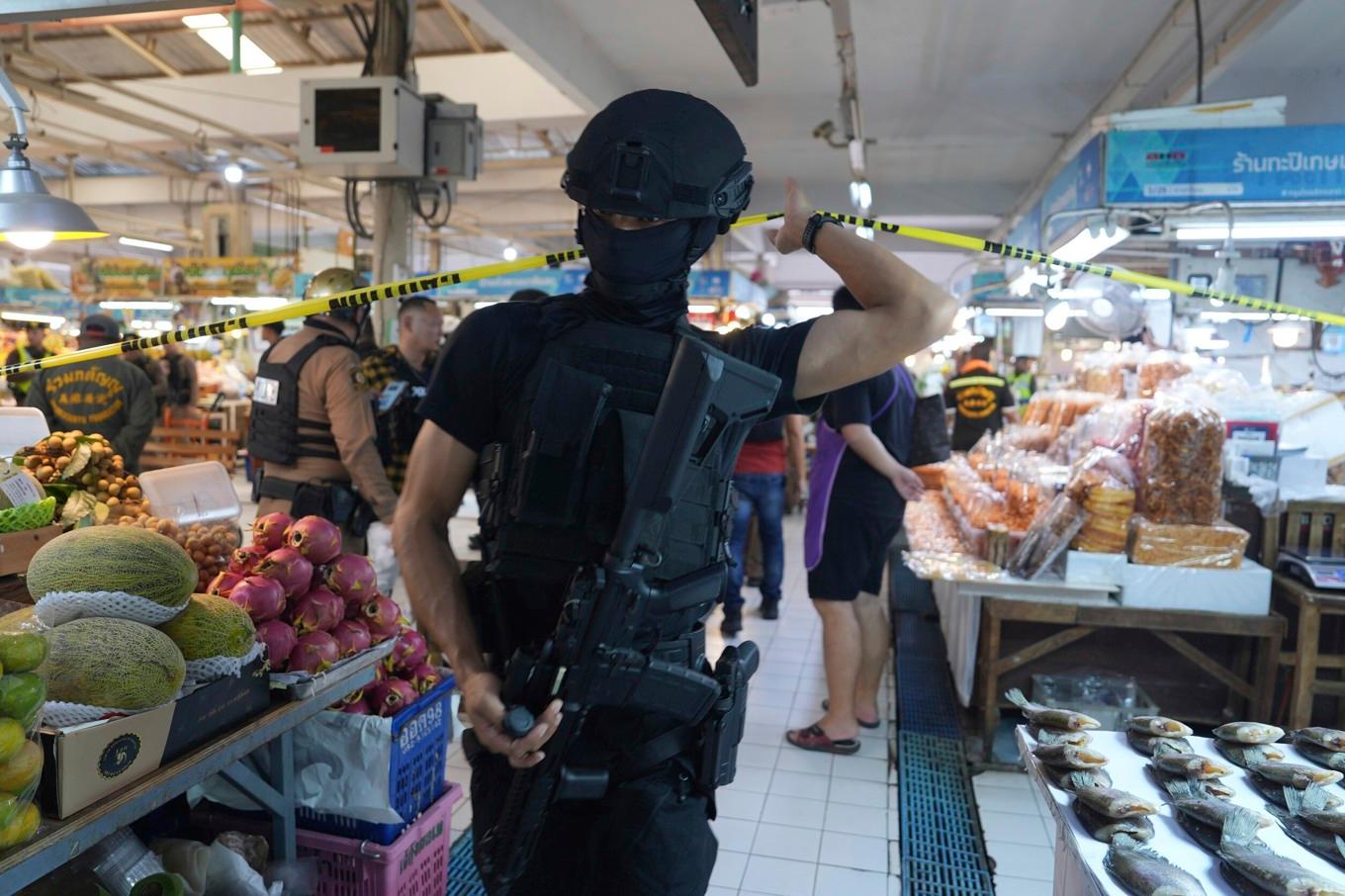 En polisman på plats på den populära matmarknaden Or Tor Kor där fem säkerhetsvakter sköts till döds på måndagen. Foto: Nava Sangthong/AP/TT