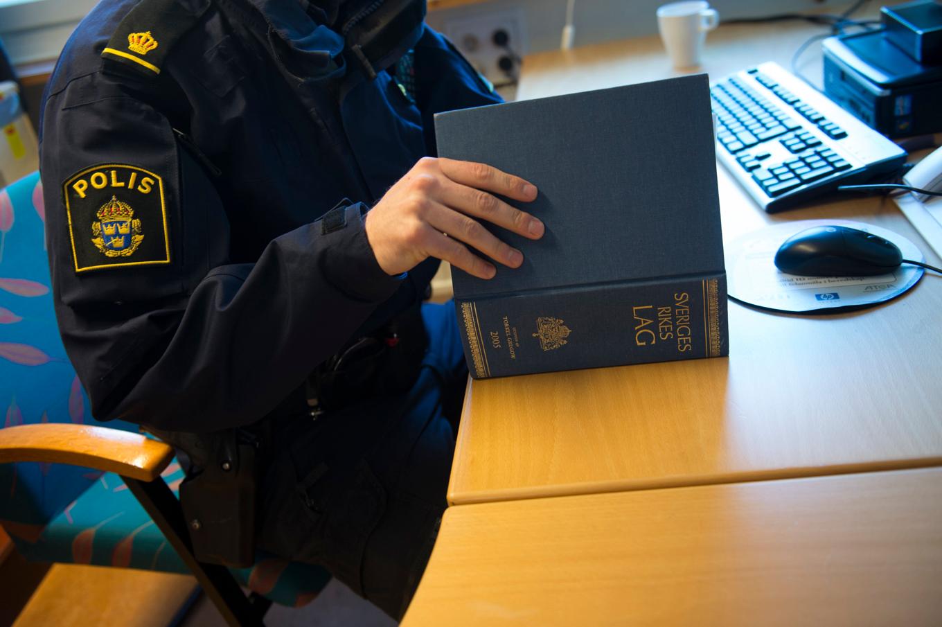 En polis med inre tjänst tittar i lagboken när han skriver en rapport på en polisstation. Arkivbild. Foto: Fredrik Sandberg/TT