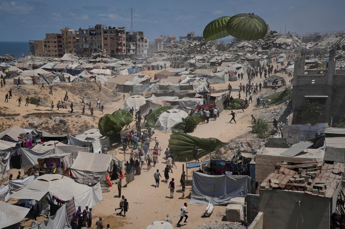 Palestinier rusar mot luftburna nödhjälpssändningar som släppts över Gaza stad. Bilden är från i torsdags. Foto: Jihad Alshrafi/AP/TT