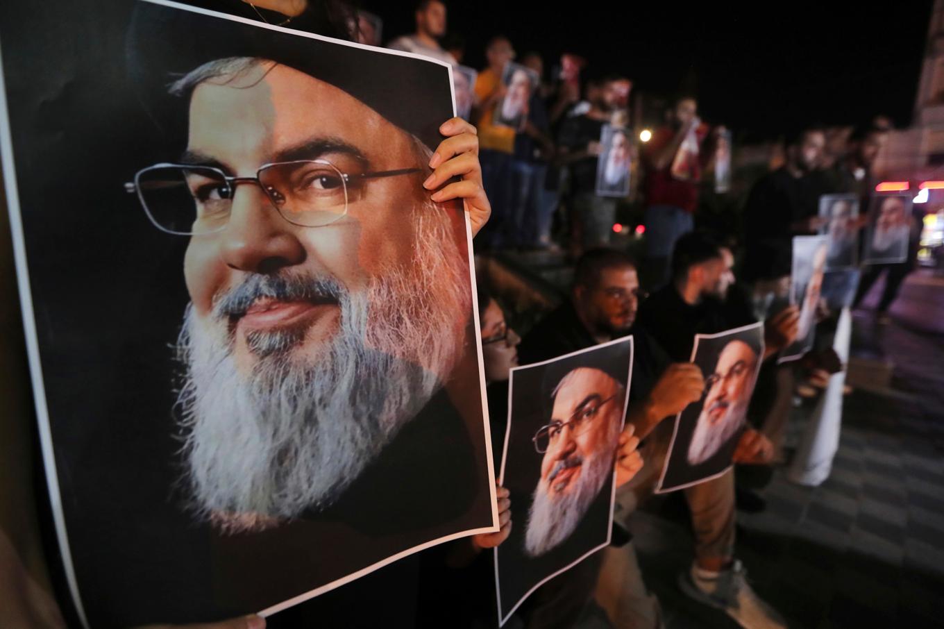 Libanesiska och palestinska män håller upp porträtt på Hizbollahledaren Hassan Nasrallah dagen efter att han dödades i ett israeliskt flygangrepp i september i fjol. Foto: Mohammed Zaatari/AP/TT