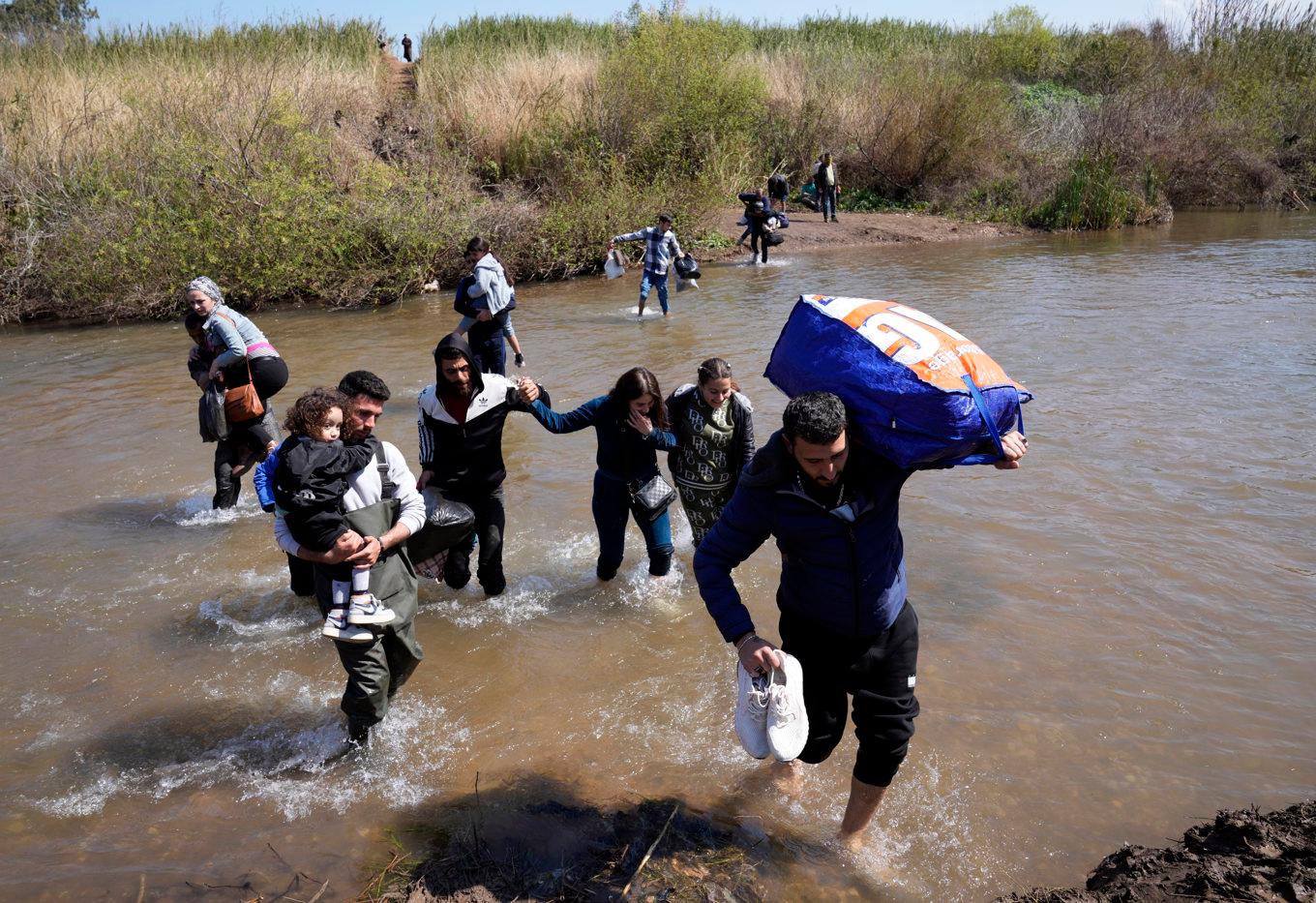 Familjer av syriska alawiter flyr över en flod. Bilden är tagen i mars i år. Foto: Hussein Malla/AP/TT