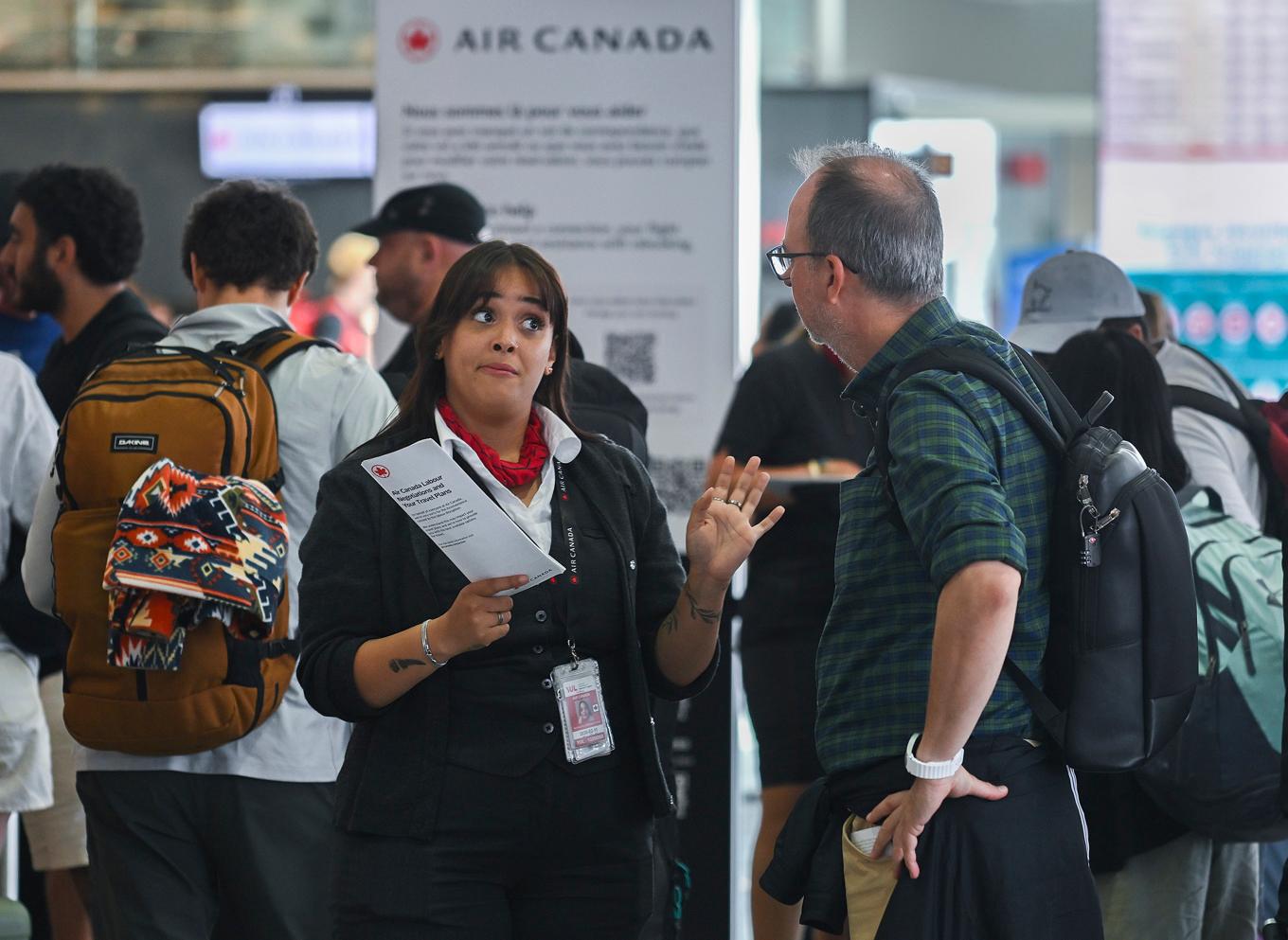 Anställd på Air Canada pratar med passagerare på flygplatsen i Montreal under lördagen. Foto: Graham Hughes/AP