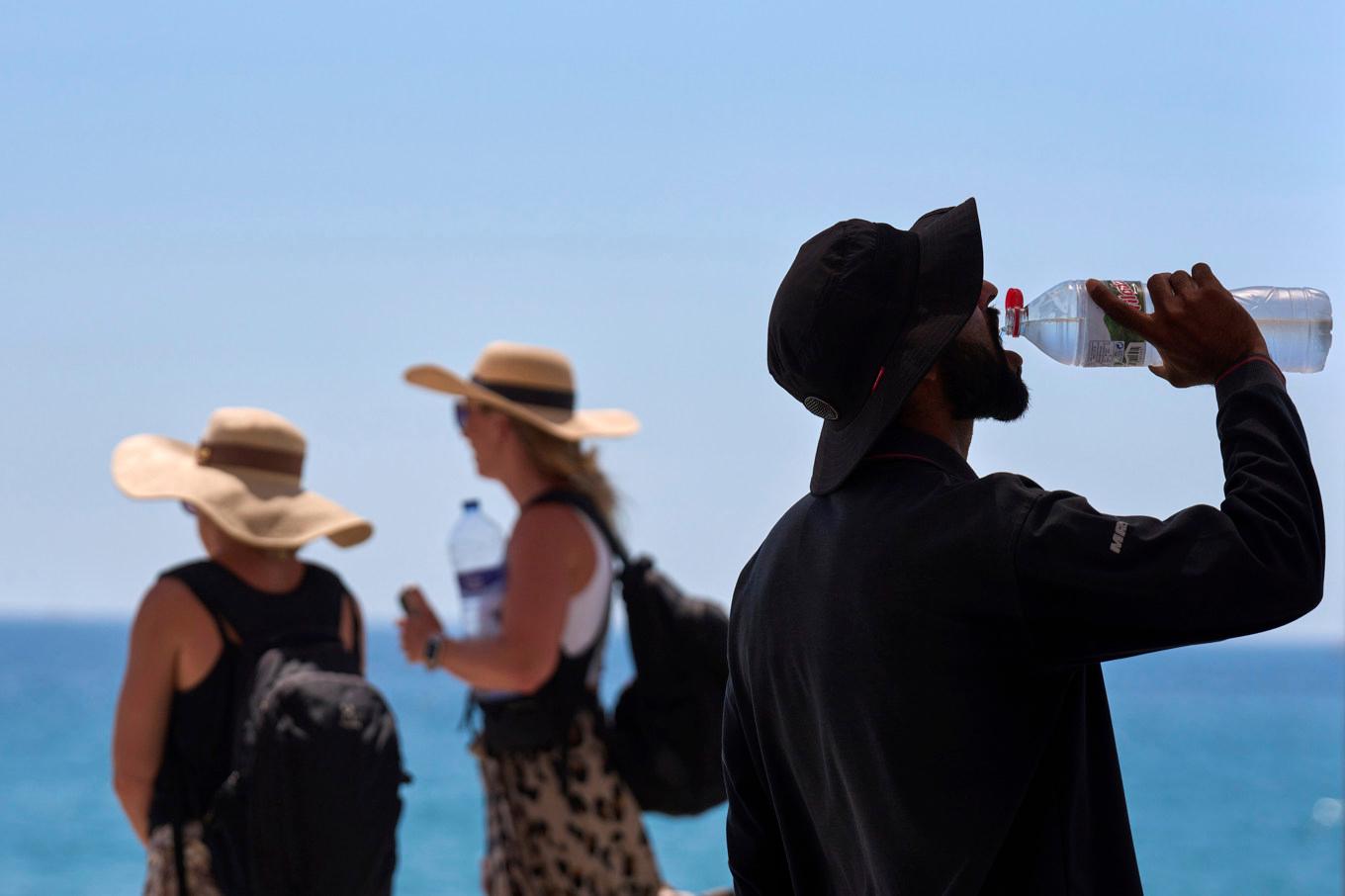 En turist dricker vatten i skuggan i Barcelona. Bild från 2 juli. Foto: Emilio Morenatti/AP/TT