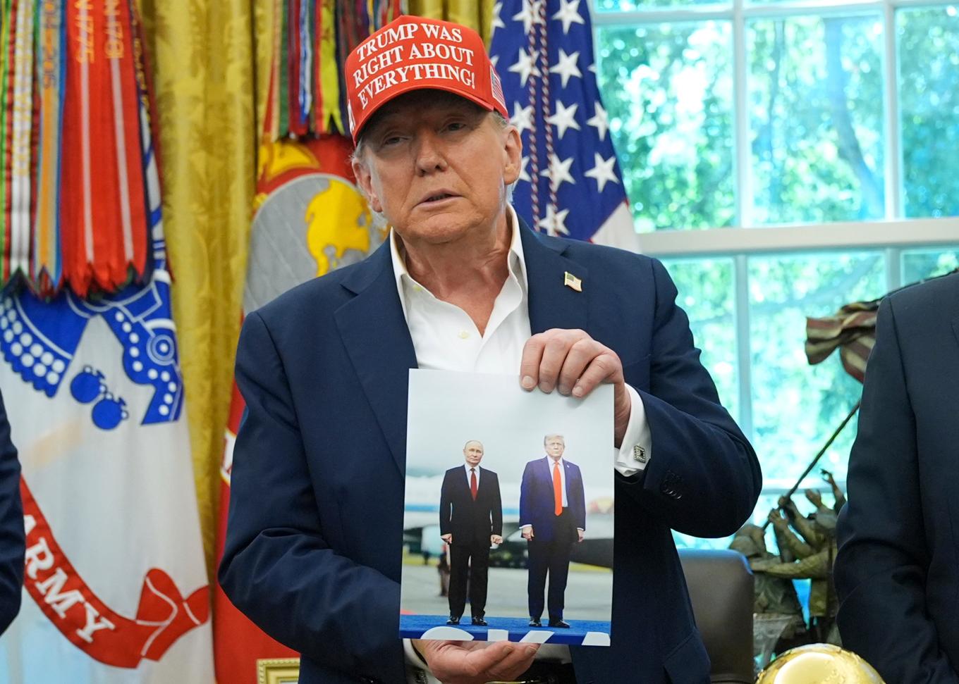 USA:s president Donald Trump håller upp ett foto av sig själv och Rysslands president Vladimir Putin från ledarnas möte i Alaska. Bilden togs i Vita huset den 22 augusti. Foto: Jacquelyn Martin/AP/TT