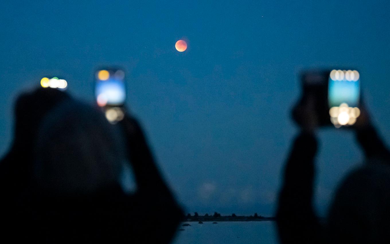 Efter en inledningsvis disig och molnig kväll fick personer i Åhus till slut möjlighet att fota blodmånen. Foto: Johan Nilsson/TT
