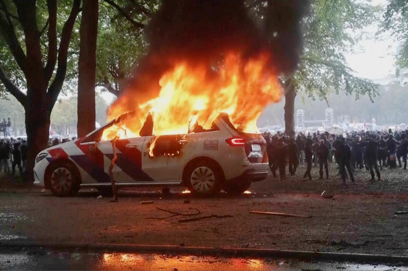 En polisbil sattes i brand i samband med en våldsam demonstration i Nederländerna på lördagen. Foto: REGIO8 via AP/TT