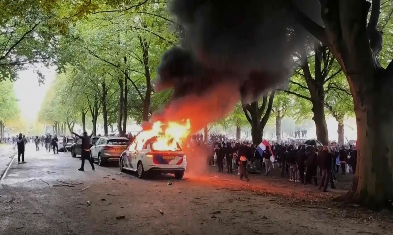 En högerextrem demonstration i Nederländerna på lördagen blev våldsam och en polisbil sattes i brand. Foto: REGIO8 via AP/TT