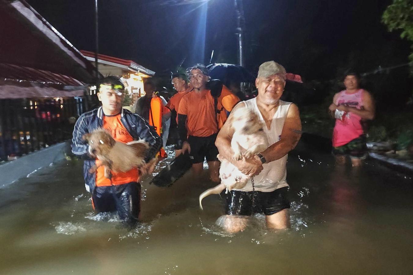 Boende och deras hundar evakueras undan stigande vattennivåer i Leyte-provinsen. Foto: Filippinernas kustbevakning/AP/TT
