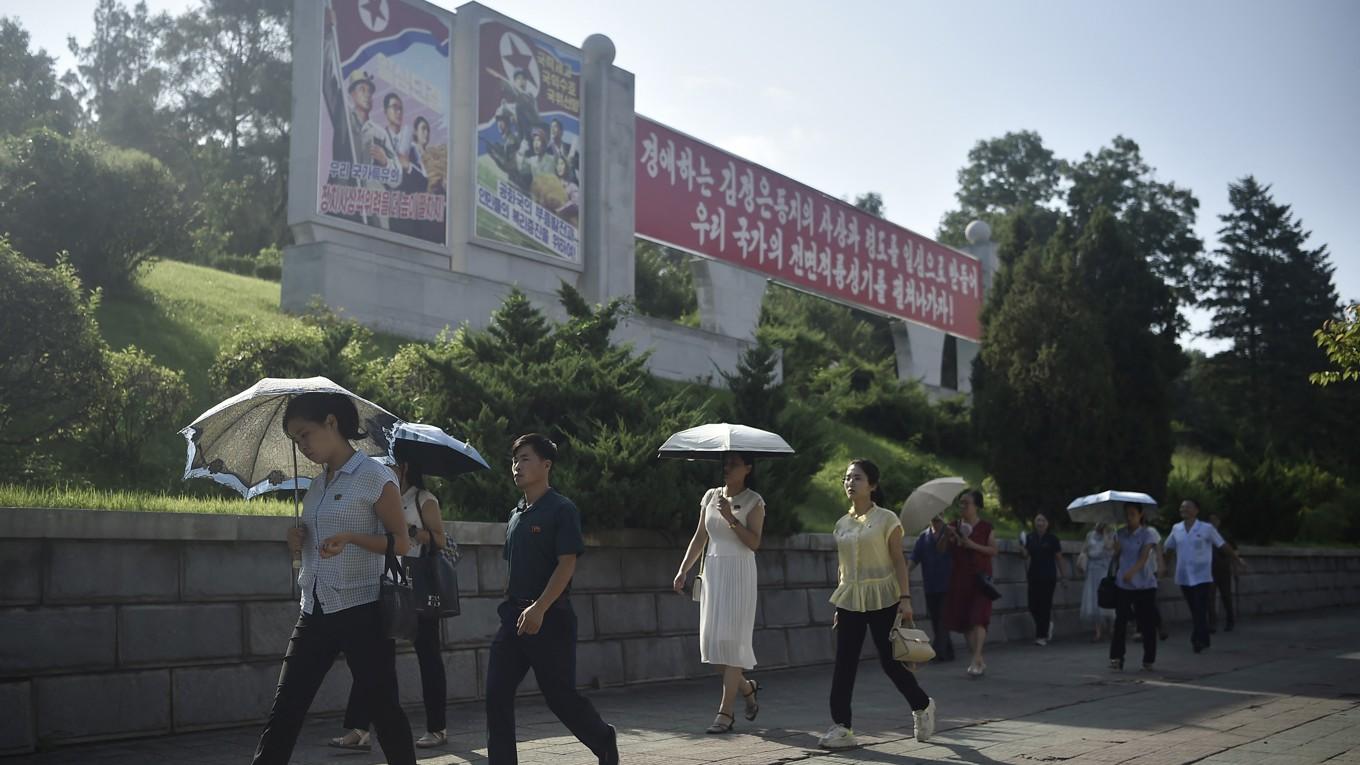 Människor går längs en trottoar nära Triumfbågen i den nordkoreanska huvudstaden Pyongyang den 3 september. (Foto av Kim Won Jin/AFP via Getty Images