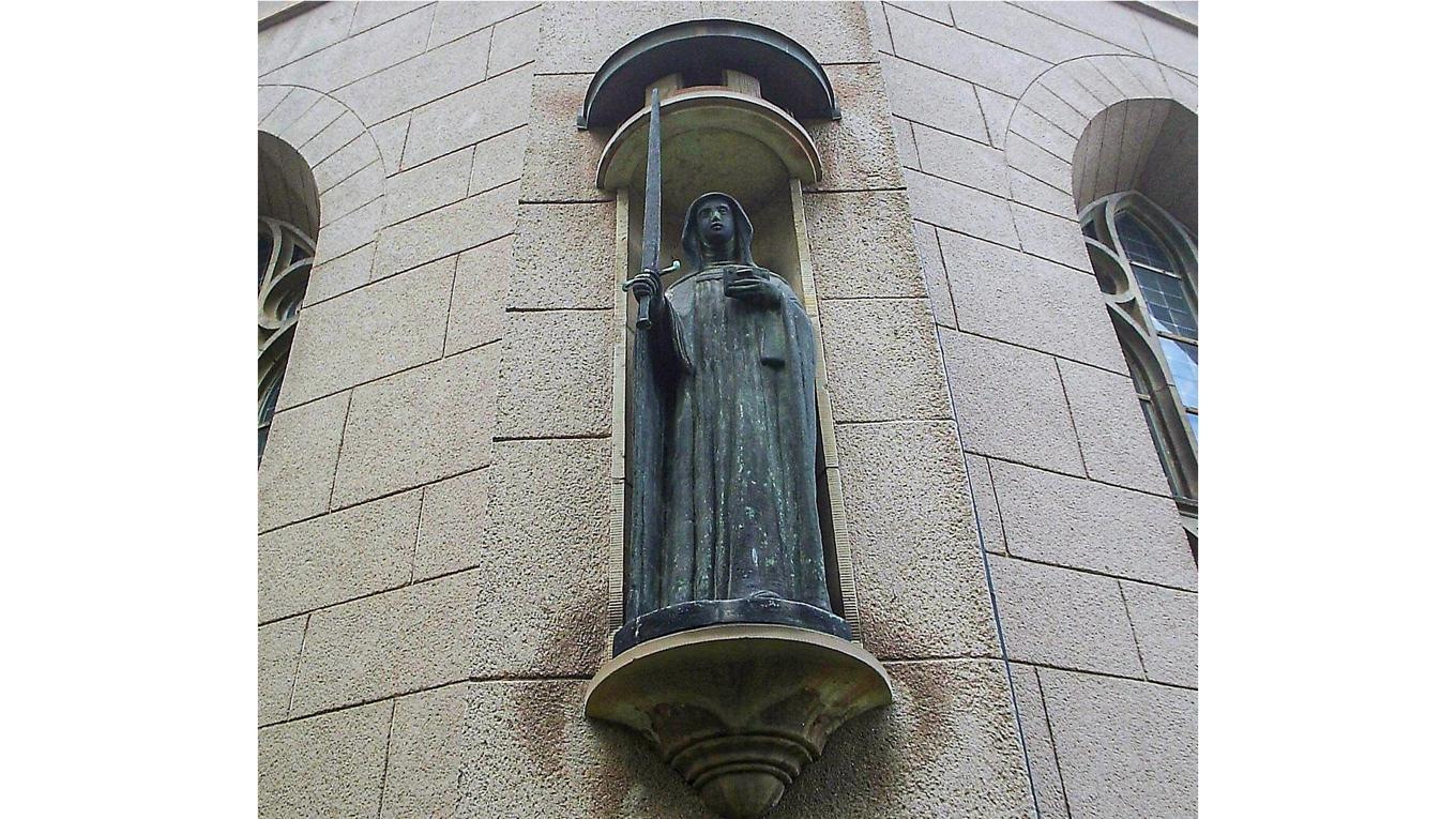 1950 skapade Astri Taube en gestaltning i brons av Elin av Skövde.
Den pryder nu Sankta Helena kyrka i Skövde. Helgonet bär sina attribut änkedoket, boken och svärdet. Foto: Harri Blomberg