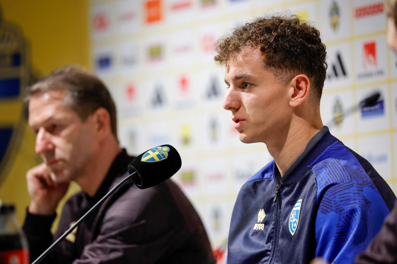 Kosovoanfallaren Fisnik Asllani på presskonferensen på Ullevi inför måndagens VM-kval mot Sverige. I bakgrunden syns förbundskapten Franco Foda. Foto: Adam Ihse/TT