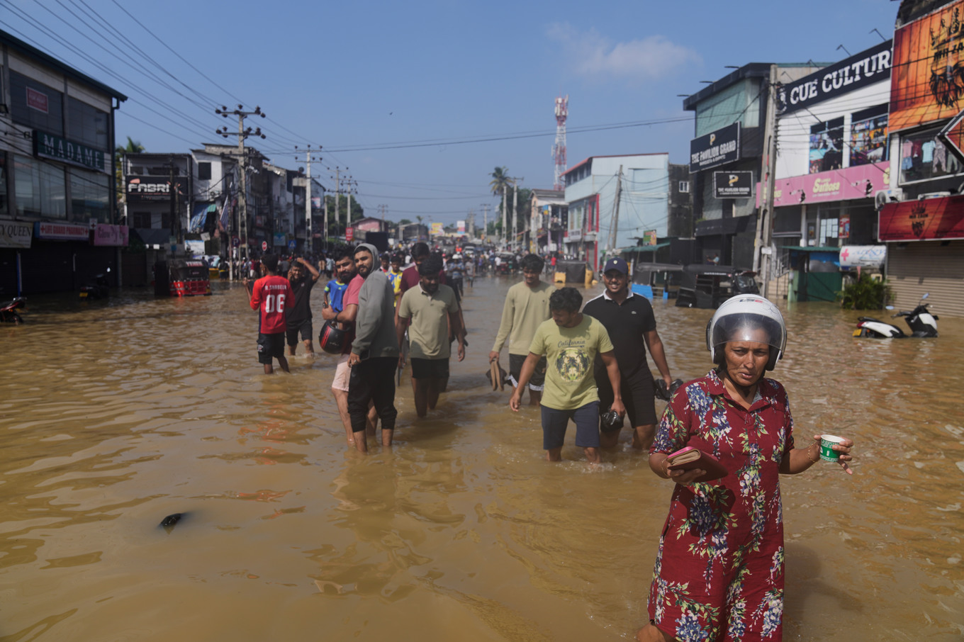 Invånare i Sri Lankas största stad, Colombo, vadar genom en översvämmad gata. Foto: Eranga Jayawardena/AP/TT