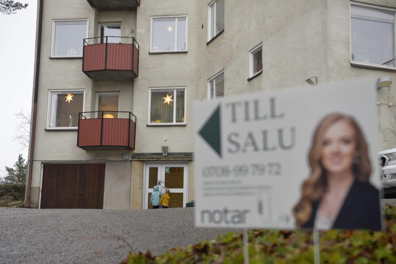 Mäklarskylt framför bostadshus. Två barn framför porten. Arkivbild. Foto: Tove Eriksson/TT