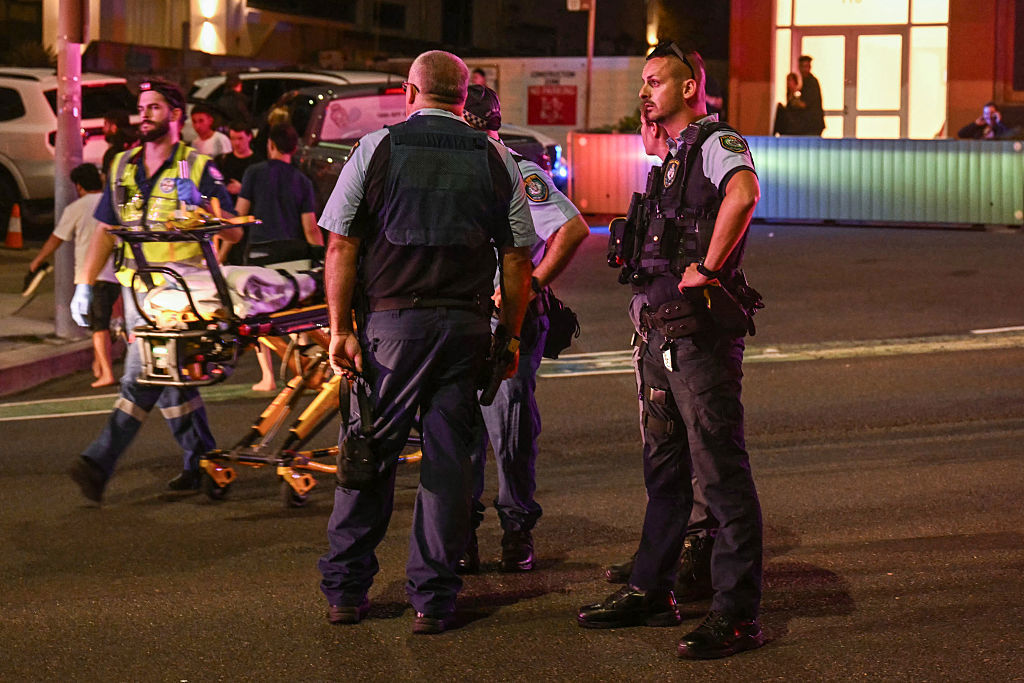 Poliser ser på medan en skadad förs bort efter terrordådet i Sydney den 14 december. Foto: Saeed Khan / AFP via Getty Images