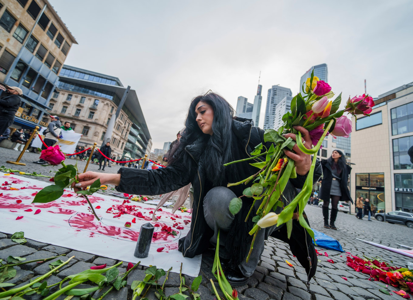 En kvinna i tyska Köln lägger ned blommor under en demonstration i solidaritet med Irans prodemokratiska protester. Bild från lördagen. Foto: Andreas Arnold/AP/TT