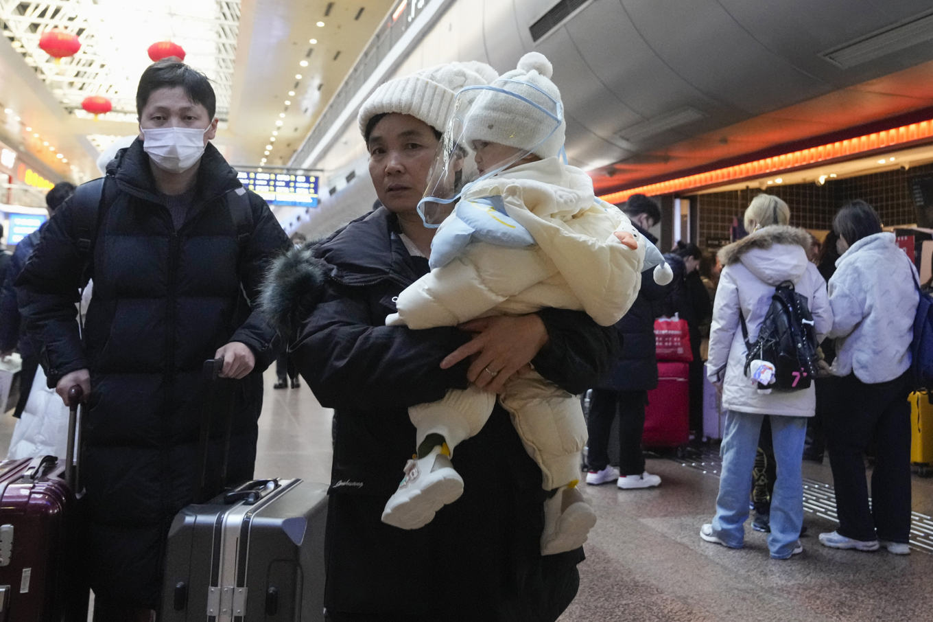 En kinesisk familj på järnvägsstationen i Peking. Arkivbild från i fjol. Foto: Aaron Favila/AP/TT
