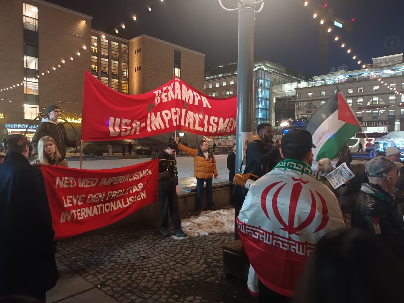 Demonstration. Banderoller, palestinaflaggan, en kvinna med tidningen Proletären och en man insvept i mullaregimens flagga. Foto: Carl S:t Clair Renard