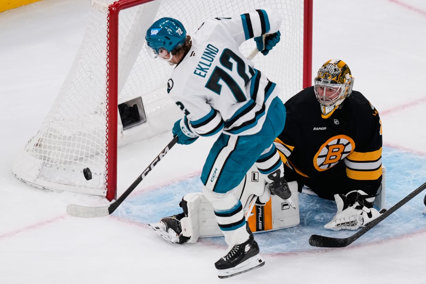 San Jose-forwarden William Eklund när han är på väg att liggandes i luften skicka in pucken bakom Bostonmålvakten Jeremy Swayman. Foto: Charles Krupa  /AP/TT