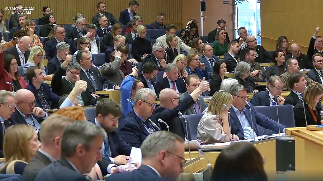 Ledamöter med tummen upp eller ner är partiernas ”riktkarlar” som visar hur partiets ledamöter ska rösta i den aktuella voteringen. Foto: Skärmbild från riksdagens webbsändning