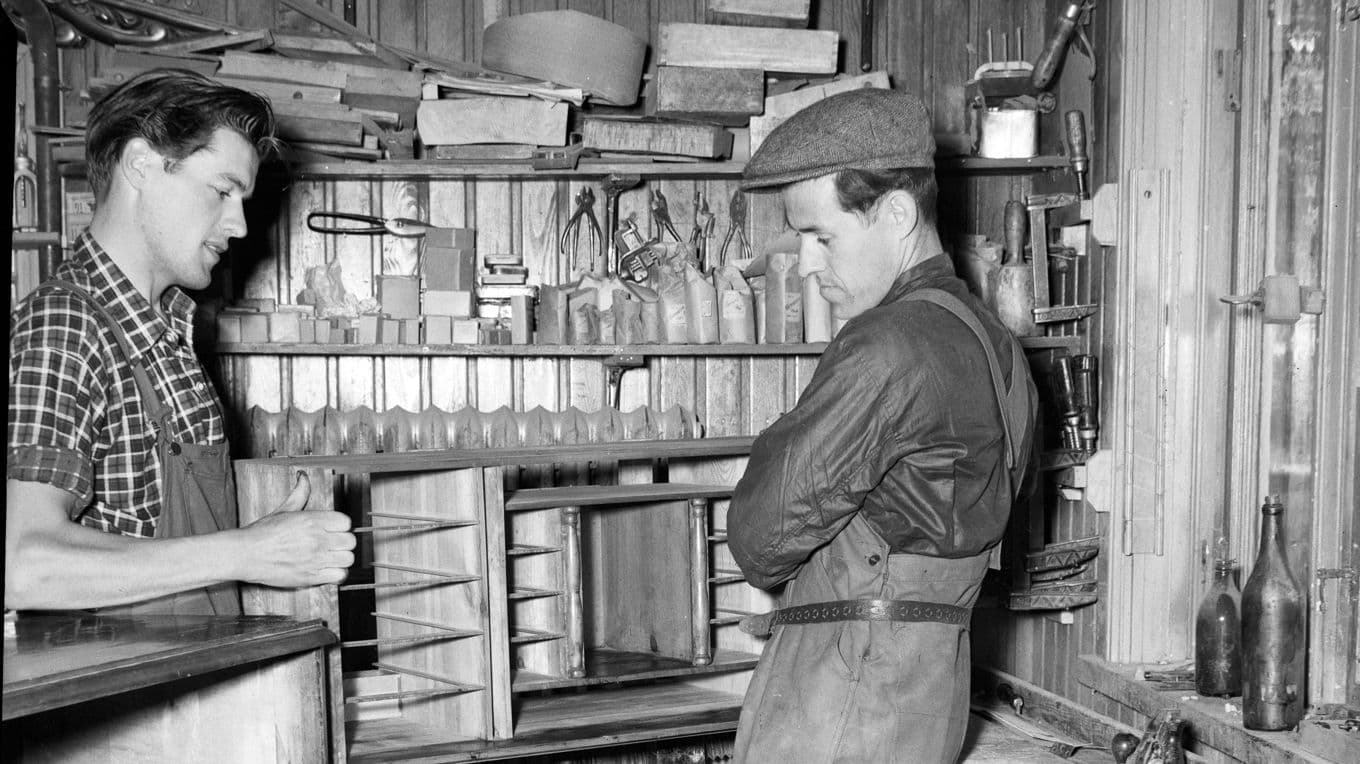 Ingemar Johansson, i rutig skjorta, diskuterar med en okänd person arbetet kring en sekretär 1952. Jönåkers Möbelverkstad Johansson & Karlsson. Foto: Press & Reportagebilder/Sörmlands museum