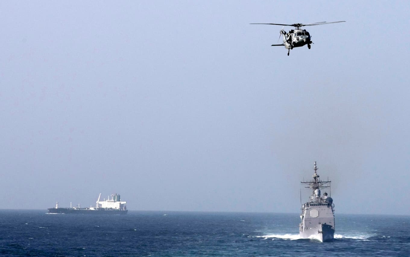 En amerikansk kryssare och en helikopter på en bild tagen från hangarfartyget USS Abraham Lincoln i Persiska viken. Arkivbild. Foto: Hassan Ammar/AP/TT