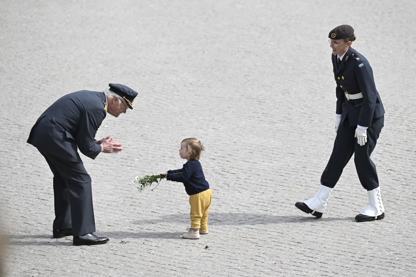 Ett litet barn ger blommor till kung Carl Gustaf. Foto: Jessica Gow/TT