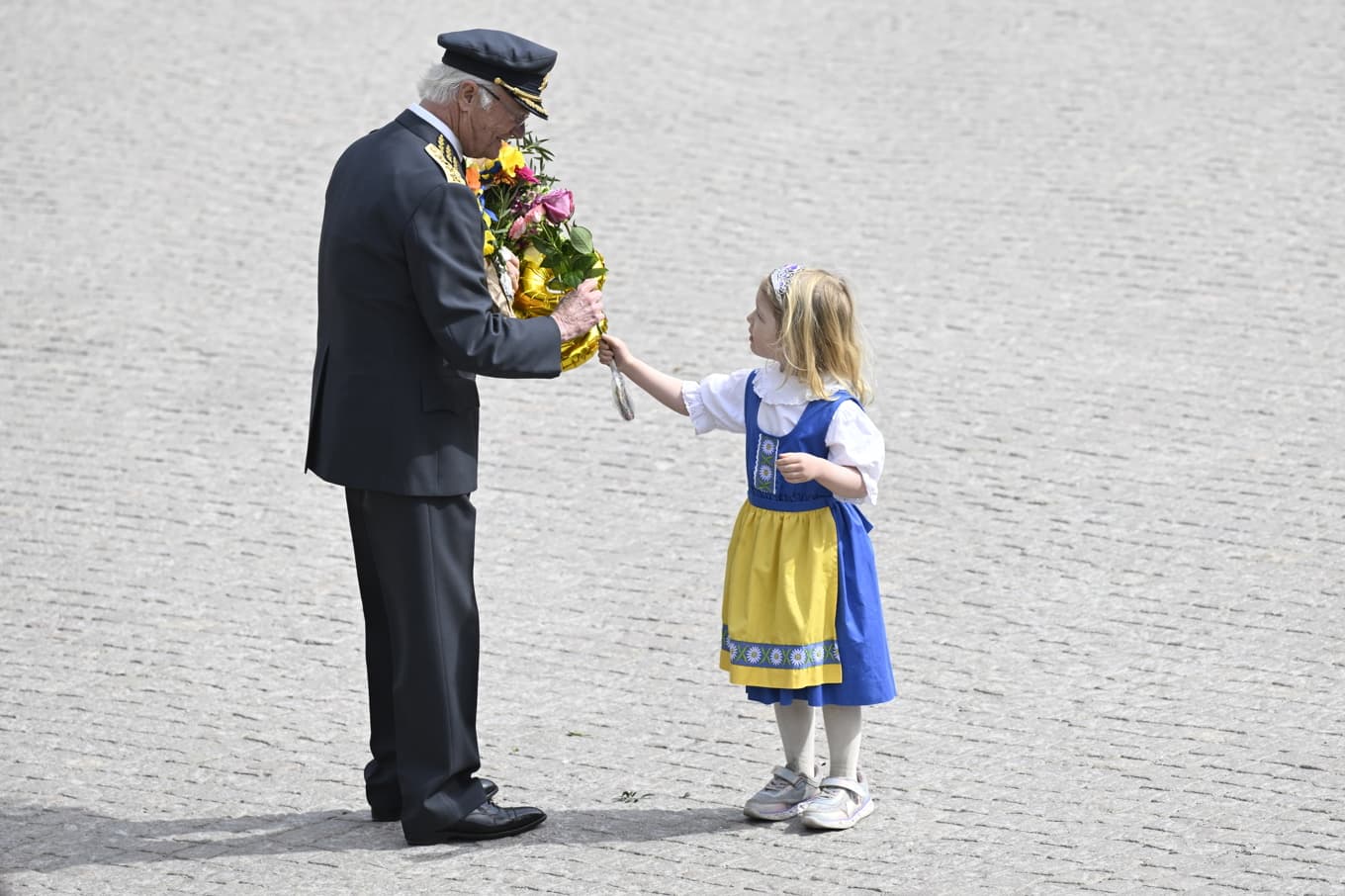 Fyraåriga Sally Leijonmarck överlämnar en blomma till kung Carl Gustaf vid firandet på yttre borggården vid Stockholms slott. Foto: Jessica Gow/TT