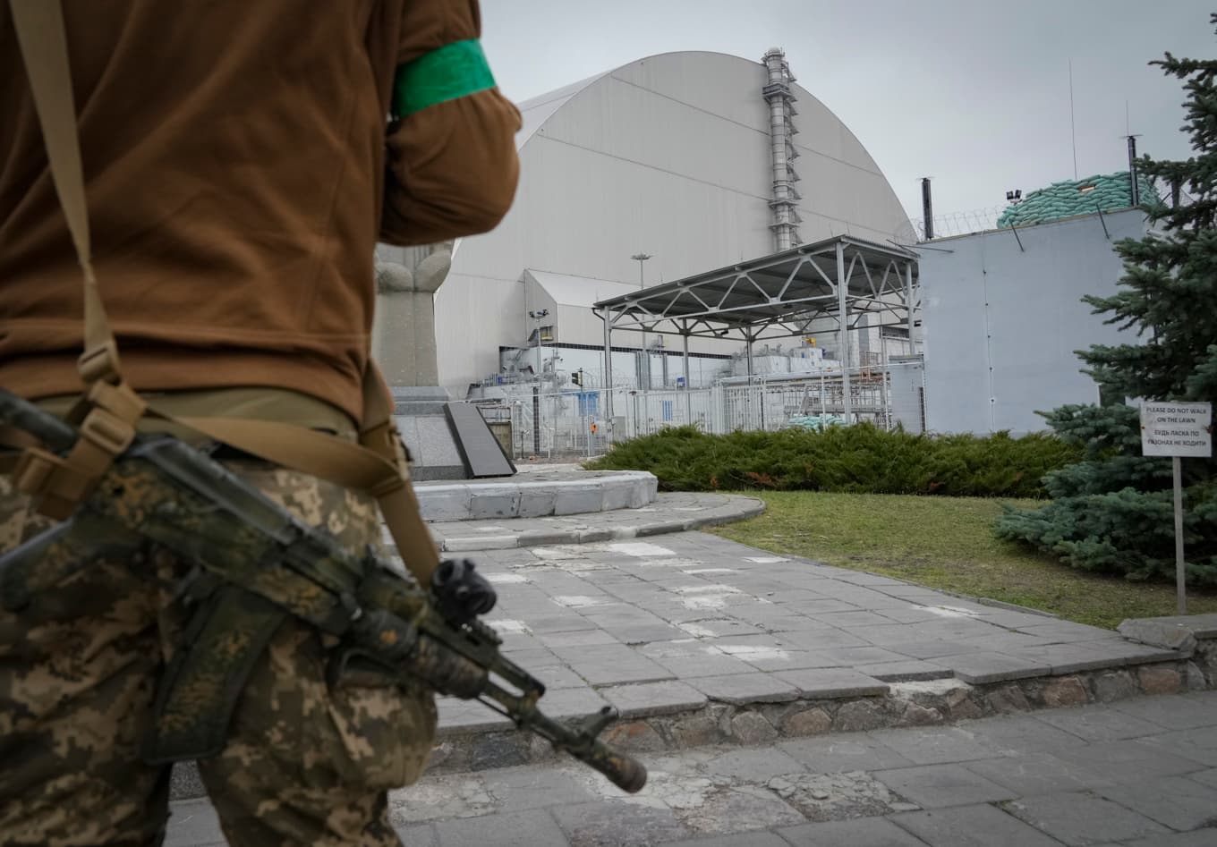 En ukrainsk soldat invid sarkofagen som täcker den exploderade reaktorn vid kärnkraftverket Tjernobyl. Bild från april 2022. Foto: Efrem Lukatsky/AP/TT
