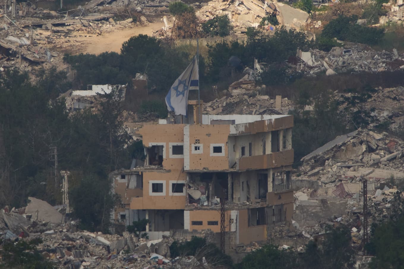 En förstört hus med israelisk flagga i södra Libanon syns från gränsen mellan Israel och Libanon. Foto: Ariel Schalit/AP/TT