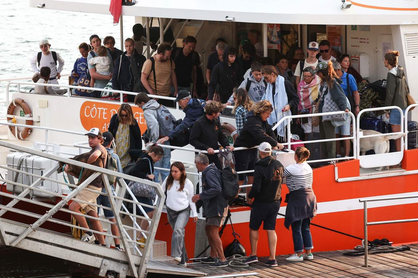 Turister i Cap Ferret flyr bränderna i båtar. Foto: Romain Perrocheau/AP/TT