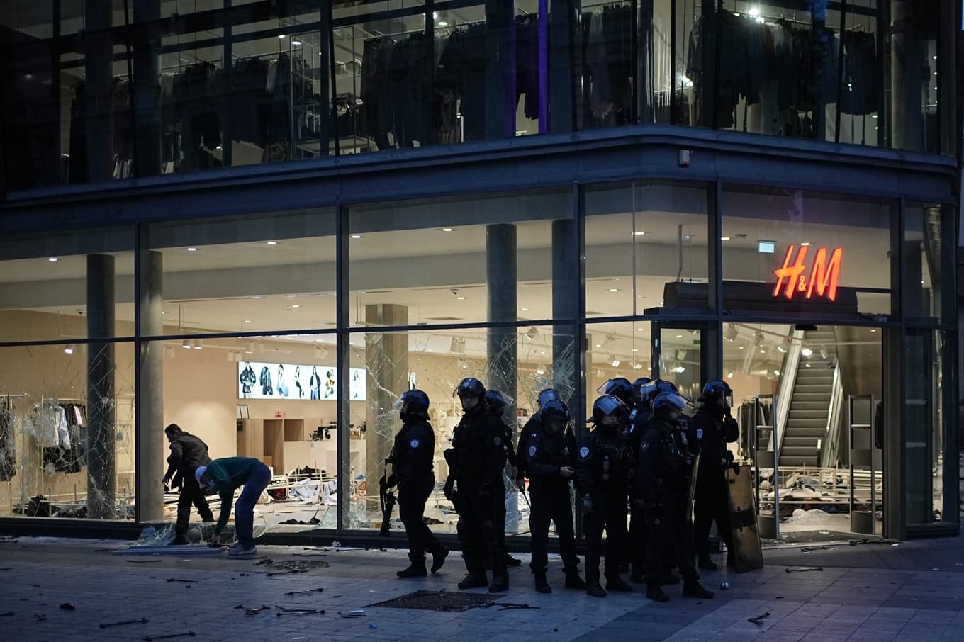 Poliser vid en delvis sönderslagen H&M-butik i Lyon den gångna helgen. Foto: Laurent Cipriani/AP/TT