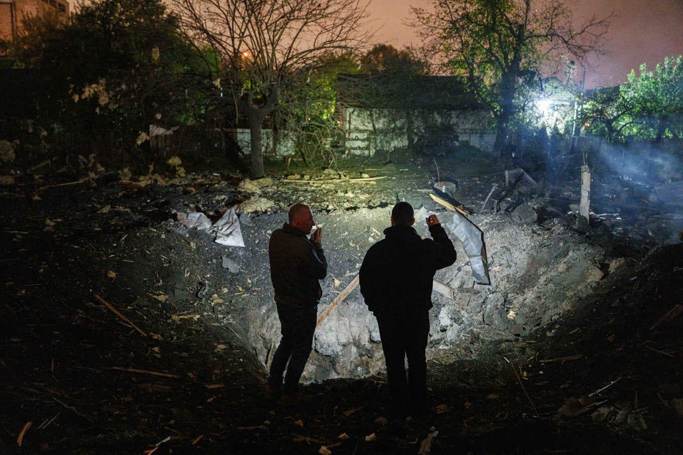 Två män vid en krater där en rysk projektil slog ner i Kiev i onsdags. Foto: Evgeniy Maloletka/AP/TT