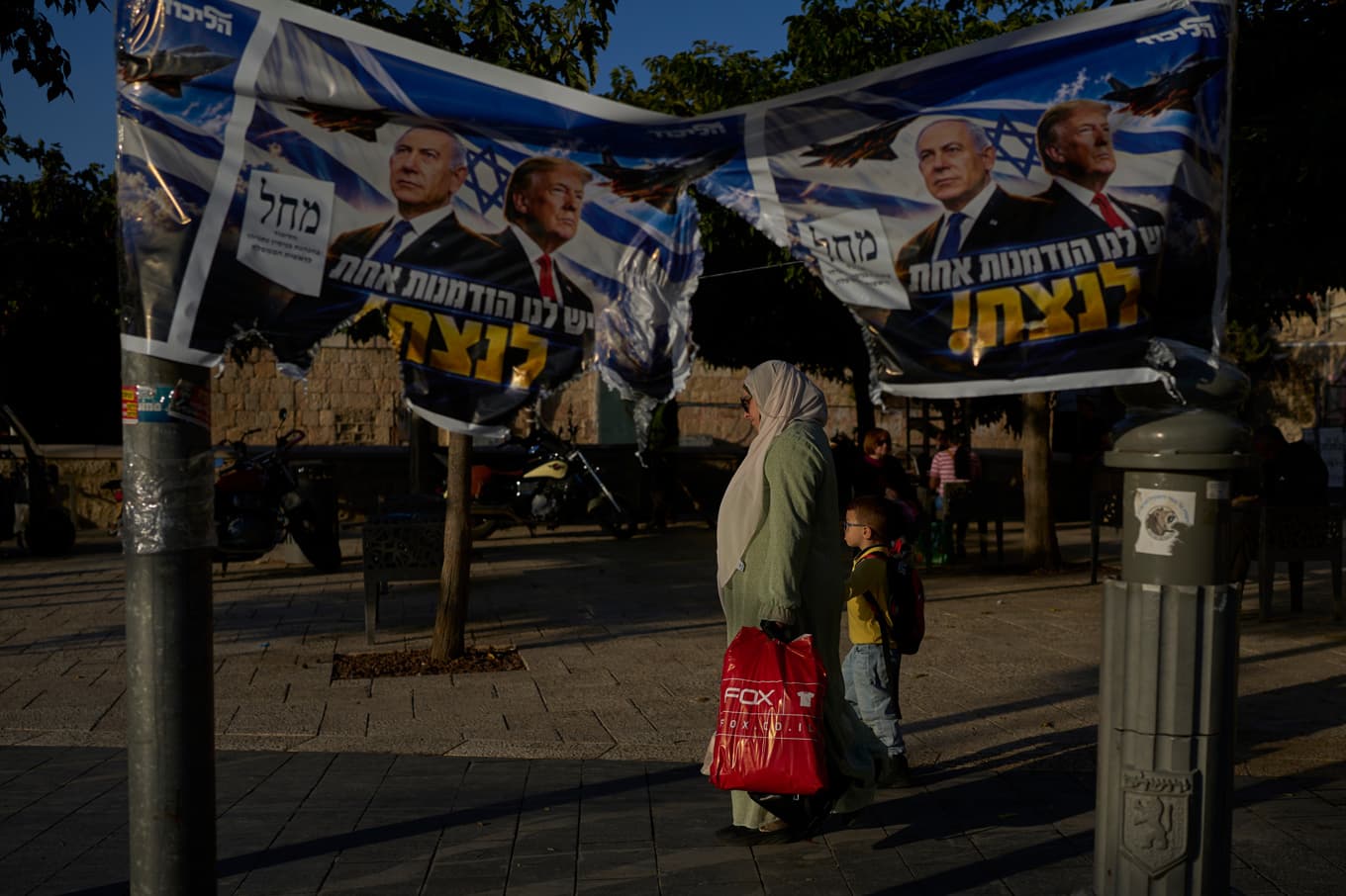 En kvinna och ett barn passerar kampanjaffischer från regeringspartiet Likud i Jerusalem på onsdagen. Foto: Ohad Zwigenberg/AP/TT