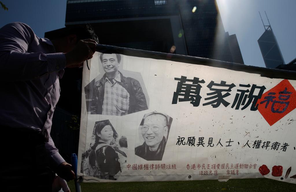 En prodemokratisk demonstrant håller upp ett tyg med bilder på den försvunne bokhandlaren Lee Bo, Nobelpristagaren Liu Xiaobo och en advokat till en kinesisk aktivist under en protest i Hongkong tidigare i veckan. (Foto: Kin Cheung/AP/TT)