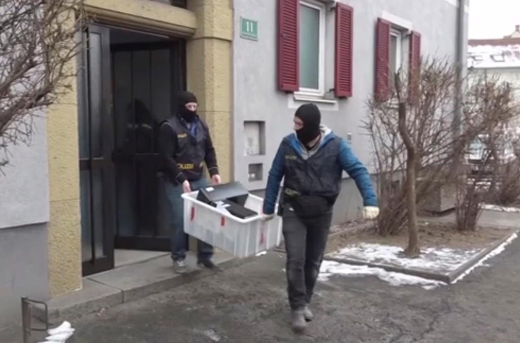 Maskerade poliser bär ut beslagtagna datorer från en byggnad under det stora tillslaget i Österrikes två största städer, Wien och Graz. (Foto: Pulz4/AP/TT)