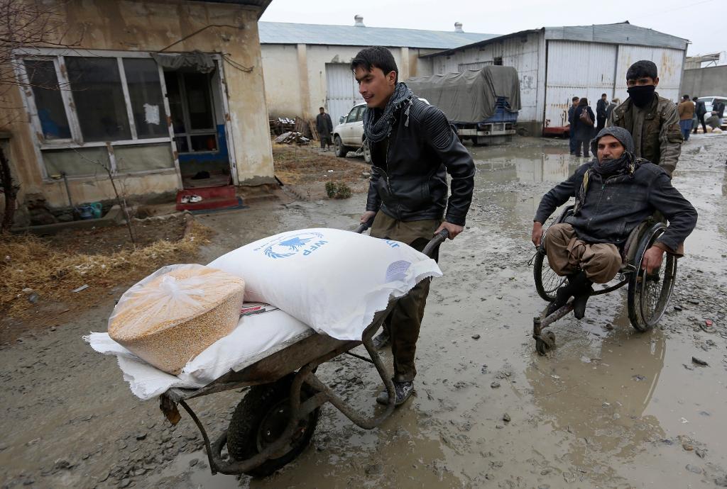 En rullstolsburen man i Afghanistan får hjälp att transportera matransoner från FN. Bilden är från slutet av januari. (Foto: Rahmat Gul/AP/TT)
