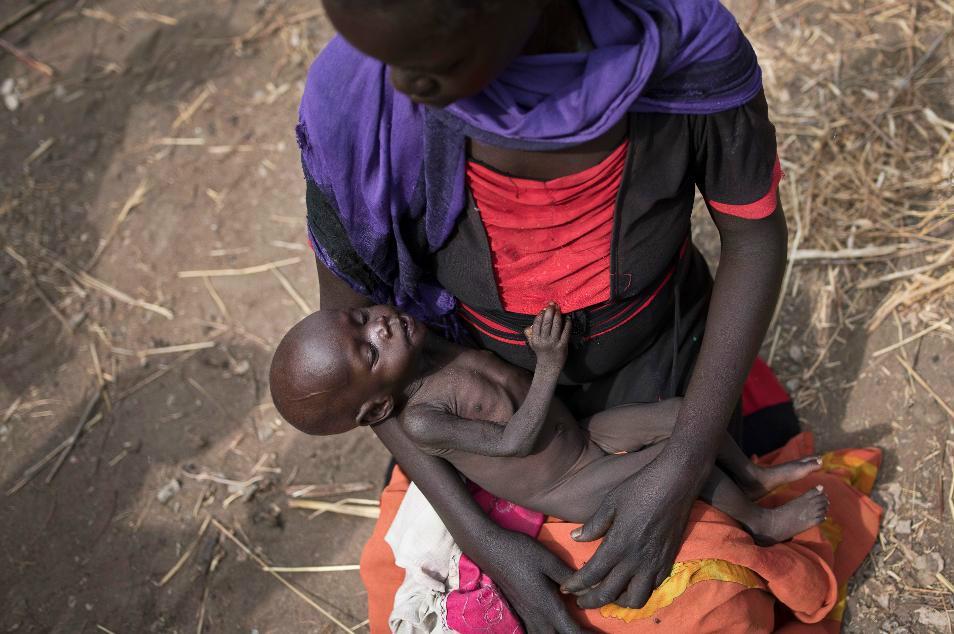 
En kvinna i Sydsudan håller sin tio månader gamla dotter i famnen, medan hon väntar på mat från en hjälporganisation. Landet är hårt drabbat av svält.  Foto: STR/AP/TT                                            