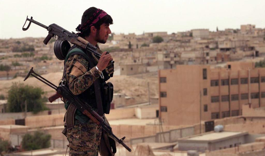 En SDF-soldat blickar ut över den syriska staden Tabqa i slutet av april. Foto: AP/TT