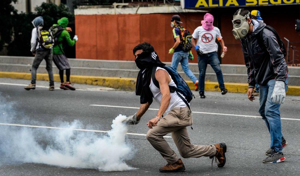 Demonstranter mot regeringen drabbar samman med kravallpolis i Caracas 13 maj. Foto: Federico Parra/AFP/Getty Images
