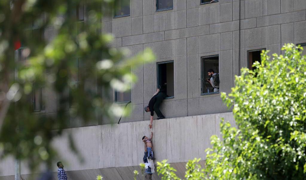


En man räcker ett barn till en säkerhetsvakt från Irans parlamentsbyggnad, en av platserna för onsdagens attentat. Foto: Omid Vahabzadeh/AP/TT                                                                                                                                    