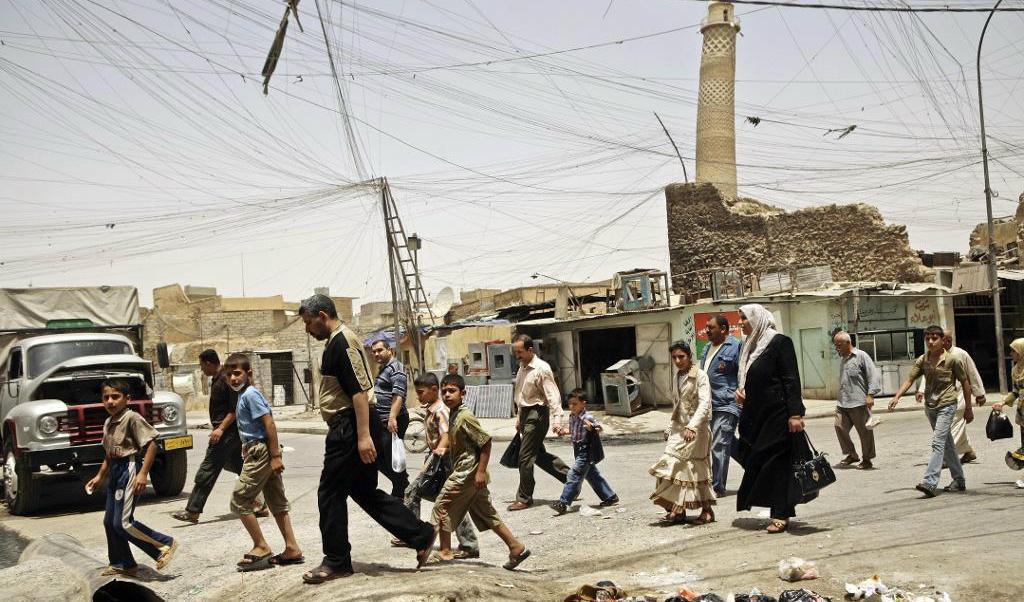 
Här, på en bild från juni 2009, går invånare i Mosul förbi den världsberömda lutande minareten. Foto: Maya Alleruzzo                                            