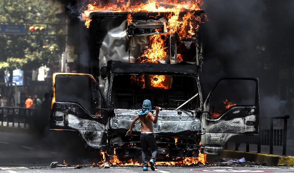 En lastbil brinner  på en avenue i Caracas i protest mot presidenten. Oppositionen utlyser en 24-timmars strejk för alla medborgare i landet. Foto: Juan Barreto/AFP/Getty Images