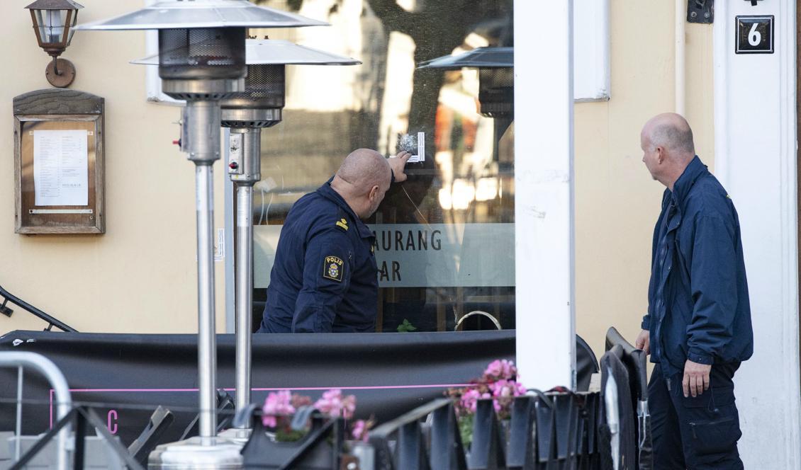 Polisens kriminaltekniker undersöker ett skotthål i en ruta på en nattklubb på Stortorget på lördagsmorgonen. Foto: Johan Nilsson/TT