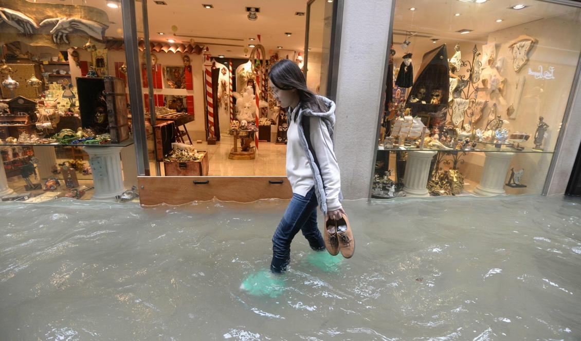 

En kvinna vadar på en översvämmad gata i Venedig. Foto: Andrea Merola/Ansa via AP/TT                                                                                        