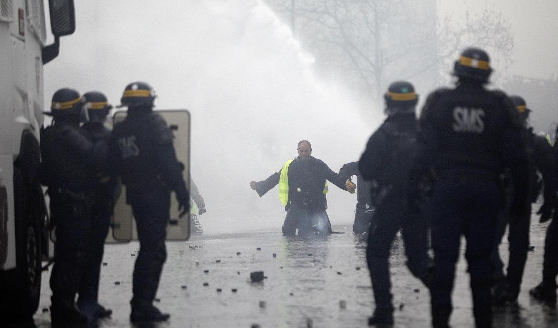 Polisen har satt in vattenkanoner mot demonstranterna i Paris. Ett 60-tal personer har gripit. Foto: Kamil Zihnioglu/AP/TT