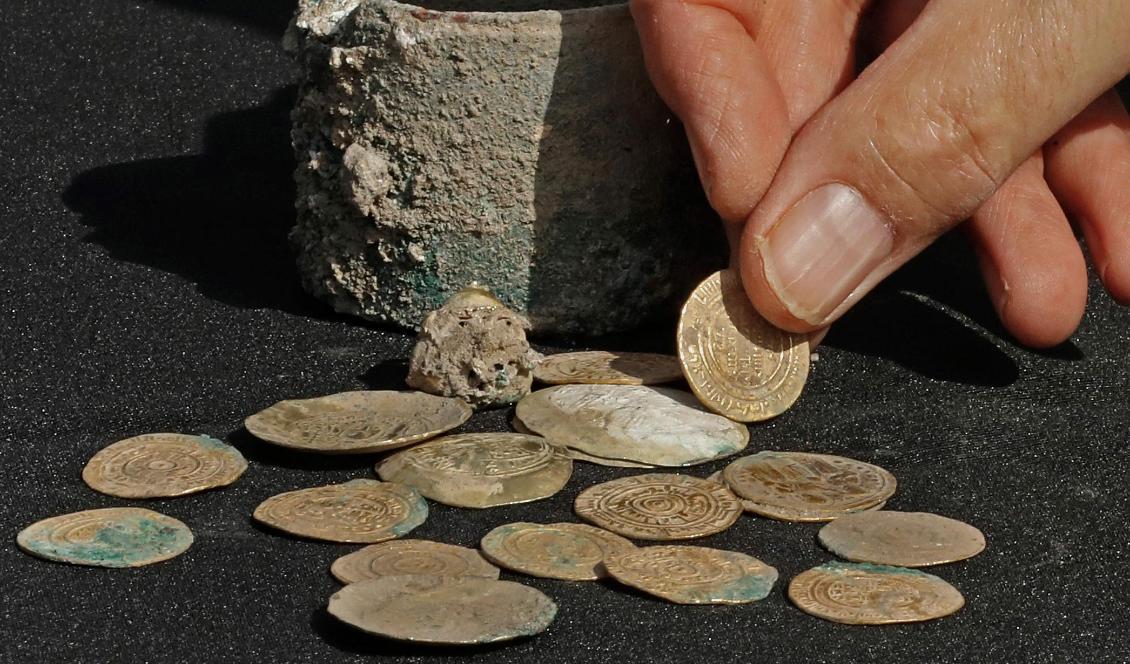 En skattgömma med 24 guldmynt och en öronring i guld har hittats i en liten bronskruka i ett gömställe i staden Caesarea i norra Israel. Foto: Jack Guez/AFP/TT